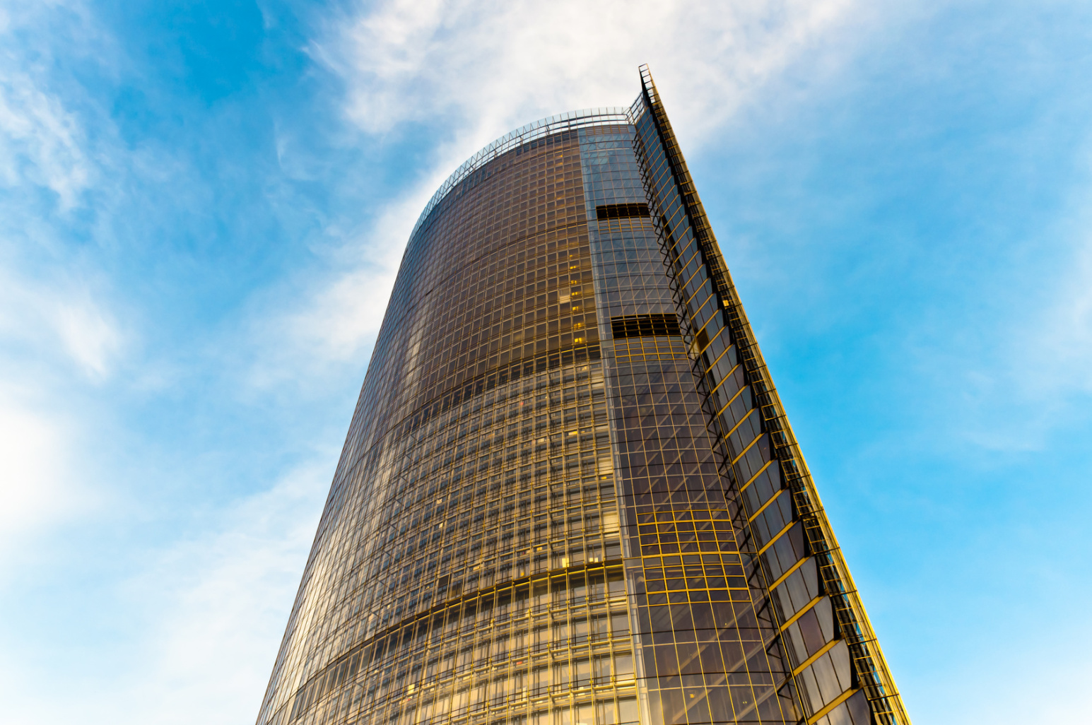 Der gelb leuchtende Post Tower in Bonn bei klarem Himmel; Kurtz Detektei Bonn