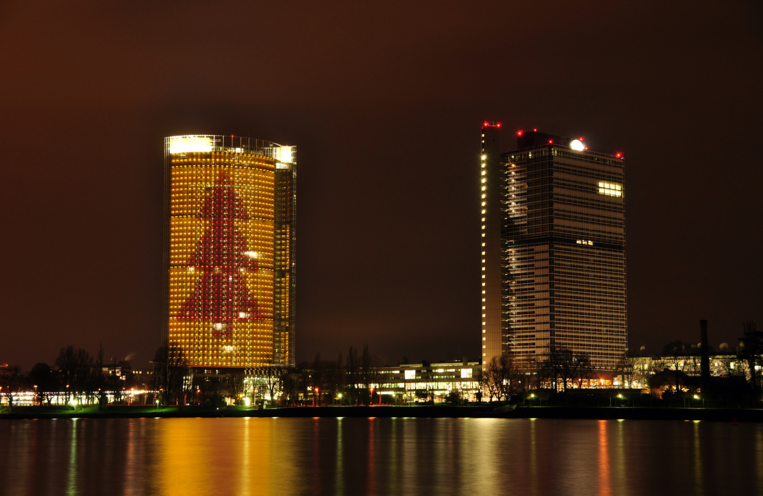 UN-Campus und Post Tower mit Tannenbaum-Beleuchtung bei Nacht mit Blick über den Rhein; Kurtz Detektei Bonn.